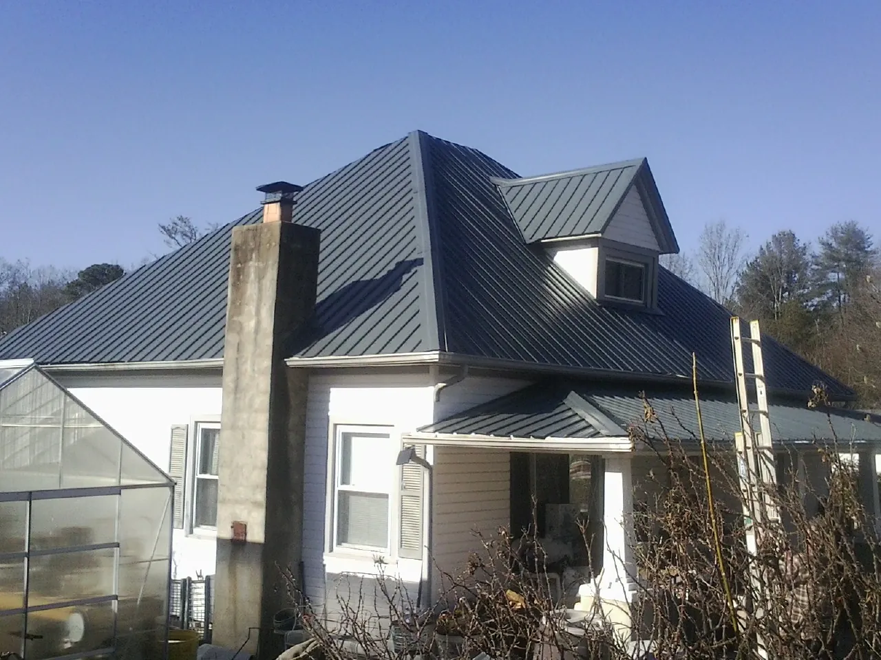 Dark blue standing seam metal roof on a white farmhouse with dormer — Slate & Tile Roof Repair by Roofing Brothers in Santa Rosa