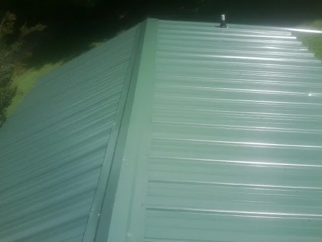 New green metal panels meeting at the ridge of a roof — Flat Roof Repair work by our crew in Santa Rosa