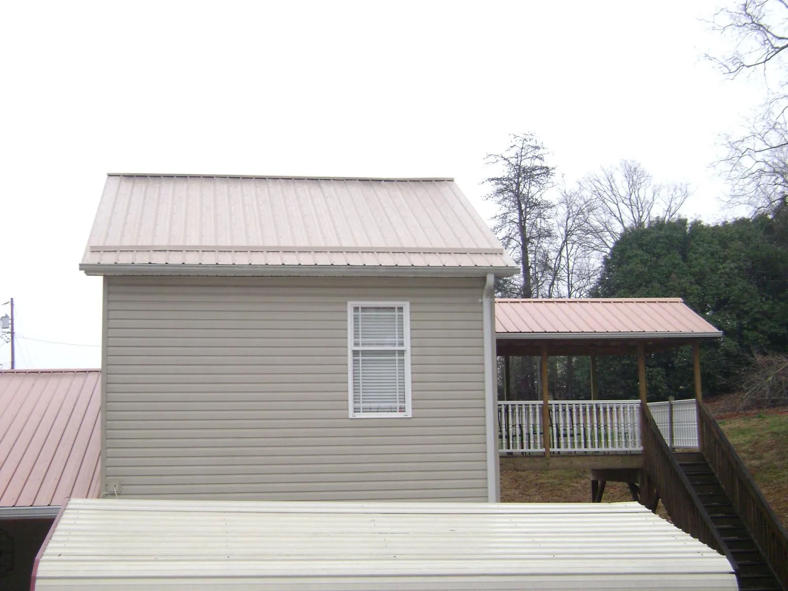 Tan metal roofs on a two story addition and attached porch, from a Roof Replacement job in Santa Rosa