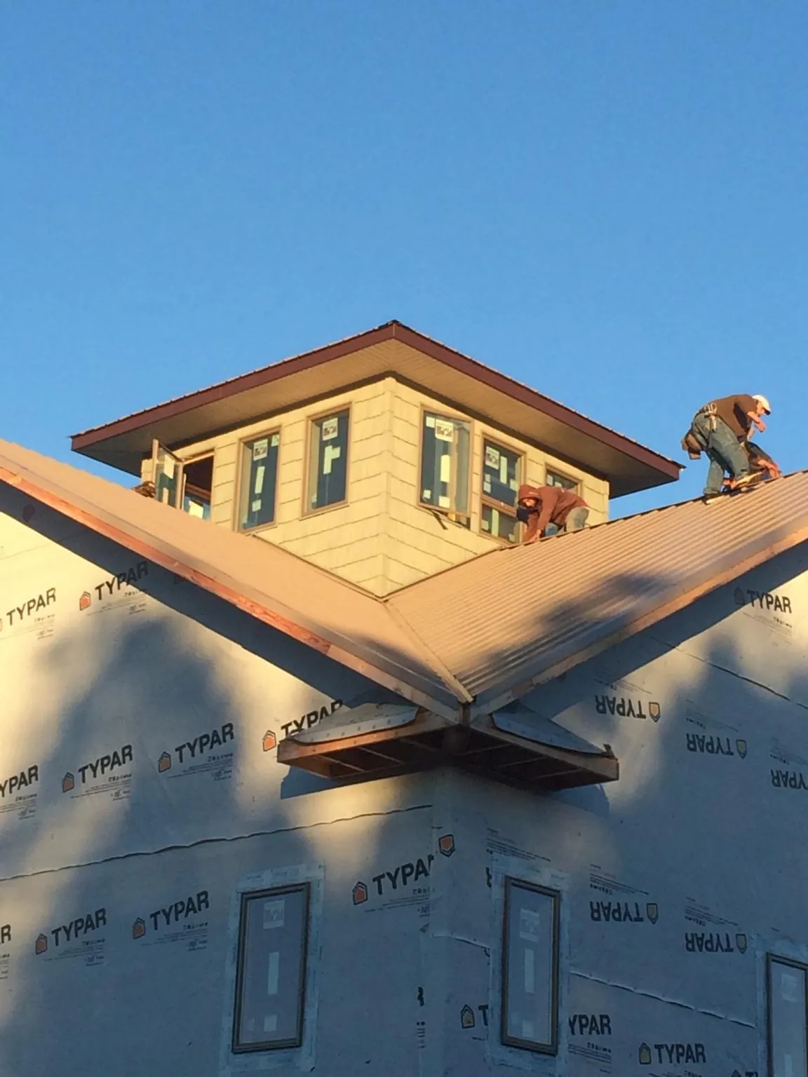 Roofers working around a rooftop cupola on a new metal roof at sunset — Roof Waterproofing in Santa Rosa by Roofing Brothers
